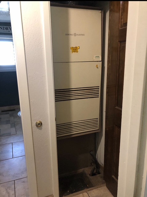 Older furnace in a narrow utility closet before replacement