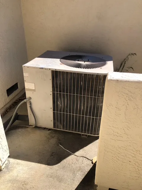 Old outdoor AC condenser unit before professional replacement