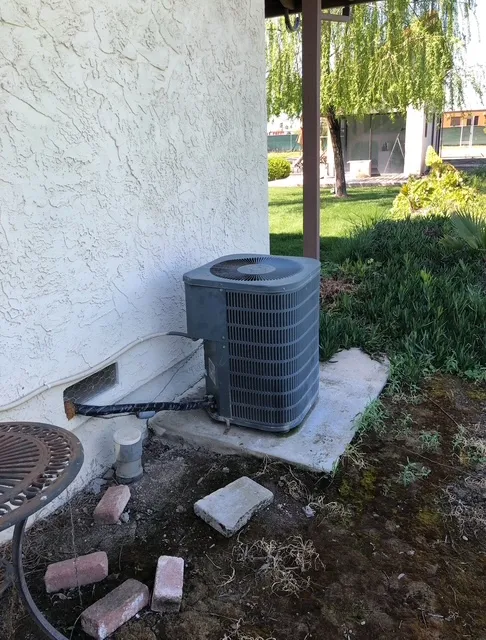 Aging outdoor AC condenser near yard before replacement